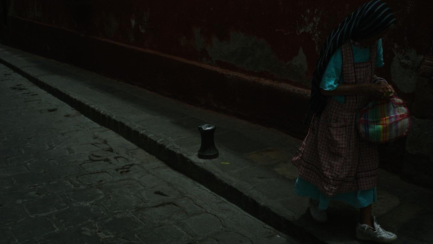 Mujer con vestido tradicional camina por una calle empedrada